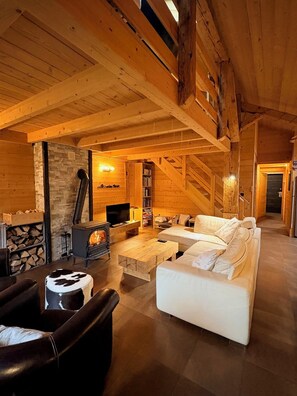 A cozy log cabin interior with a fireplace, wooden furniture, and a stone wall. - Warm and spacious duplex in Abondance farmhouse 135m2 (La Chapelle-d'Abondance)