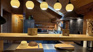 Una cocina con vigas de madera, luces colgantes, encimera de madera y diversos electrodomésticos.