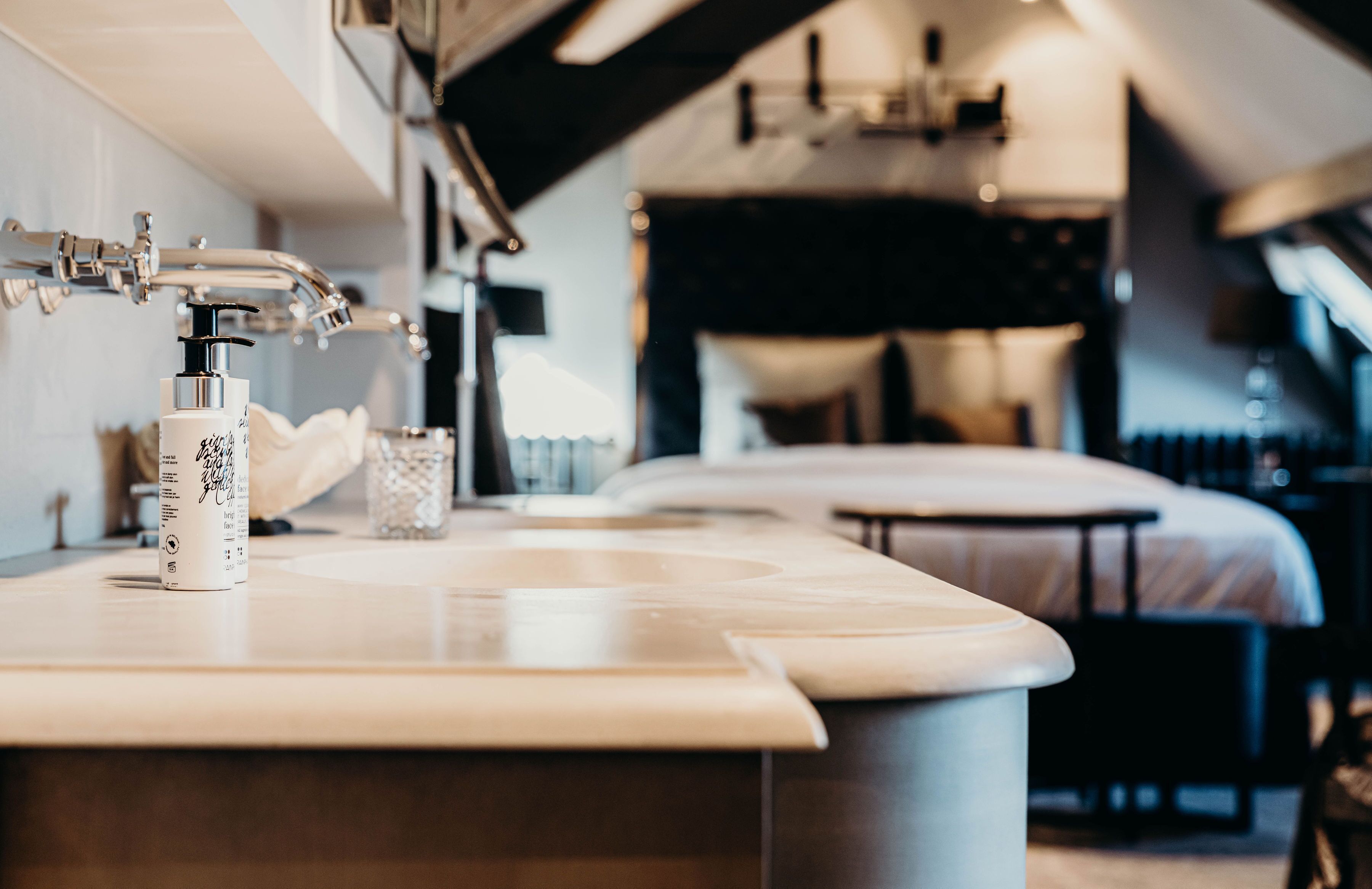 A modern bathroom with a marble countertop, a soap dispenser, and a glass.