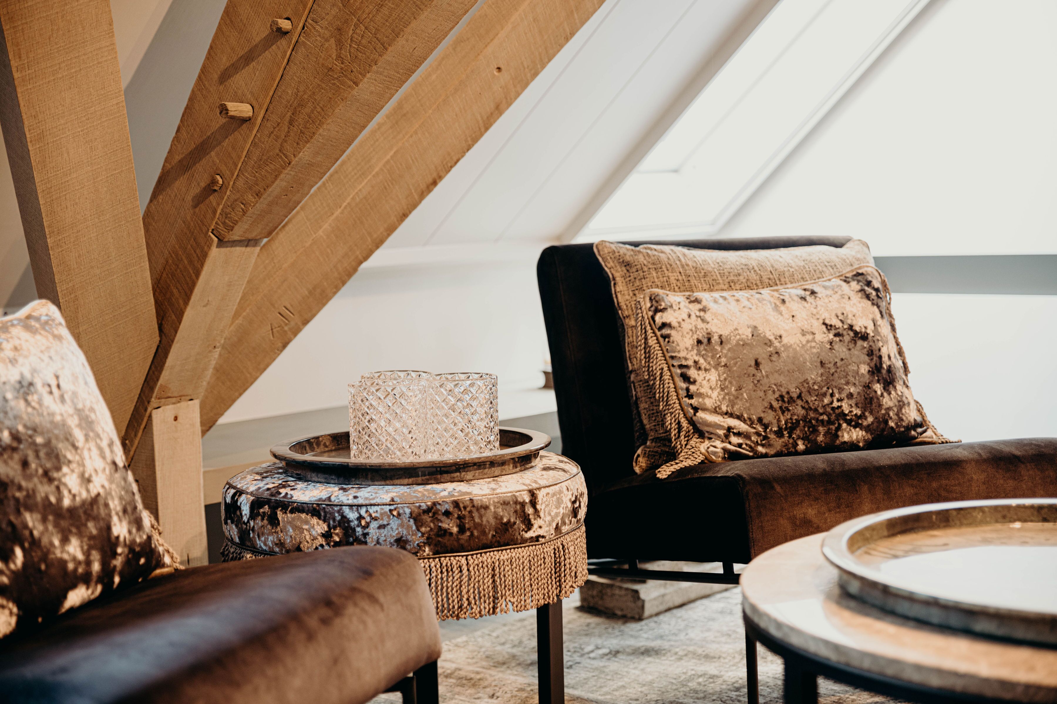 A cozy loft-style room with a sloped ceiling, a cushioned sofa with a patterned throw pillow, a round coffee table, and a small side table with a decorative item.