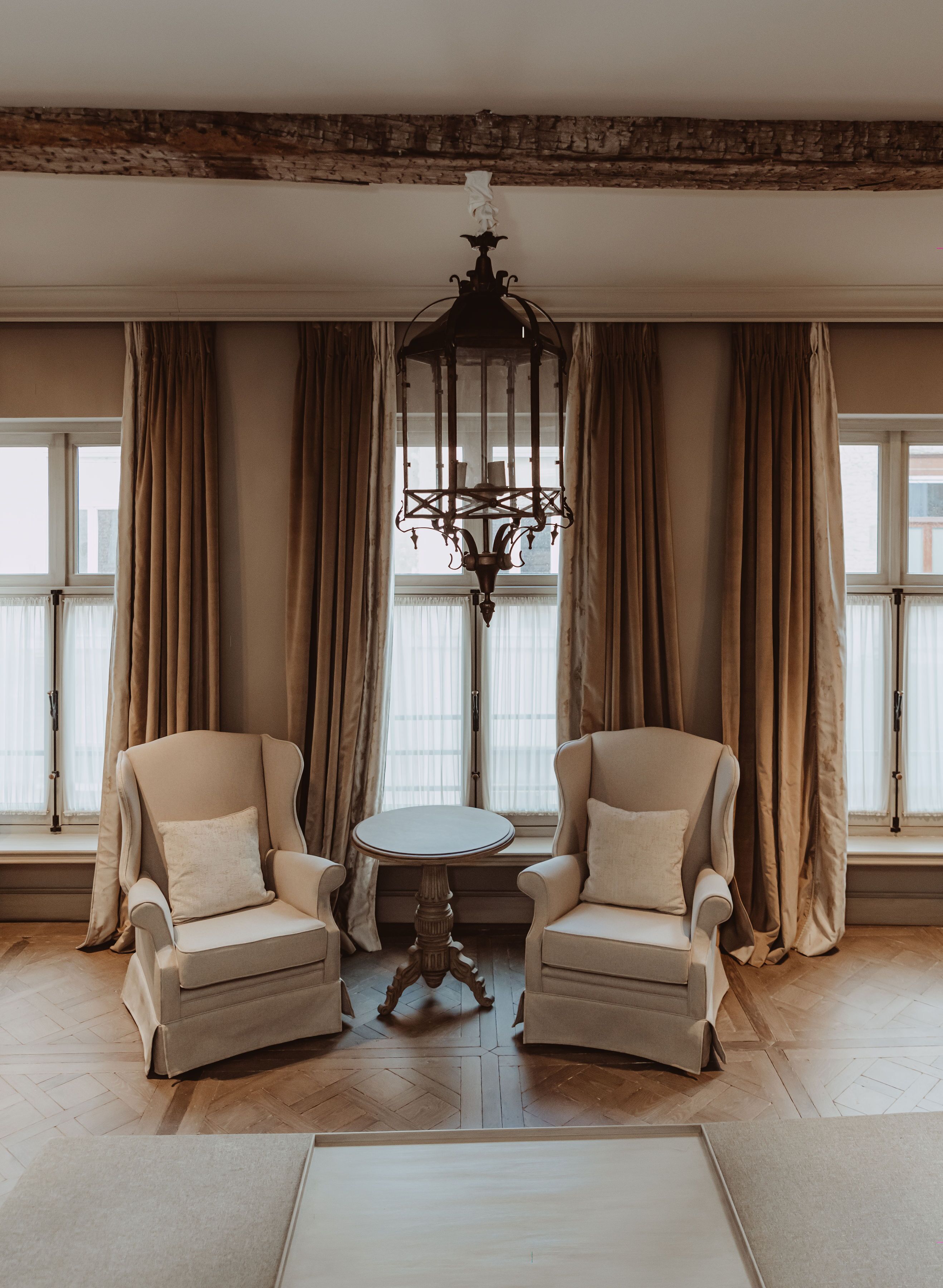 A room with two armchairs, a small round table, and a chandelier.