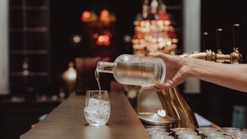 Eine Hand gießt eine klare Flüssigkeit aus einer Flasche in ein Glas mit Eiswürfeln.