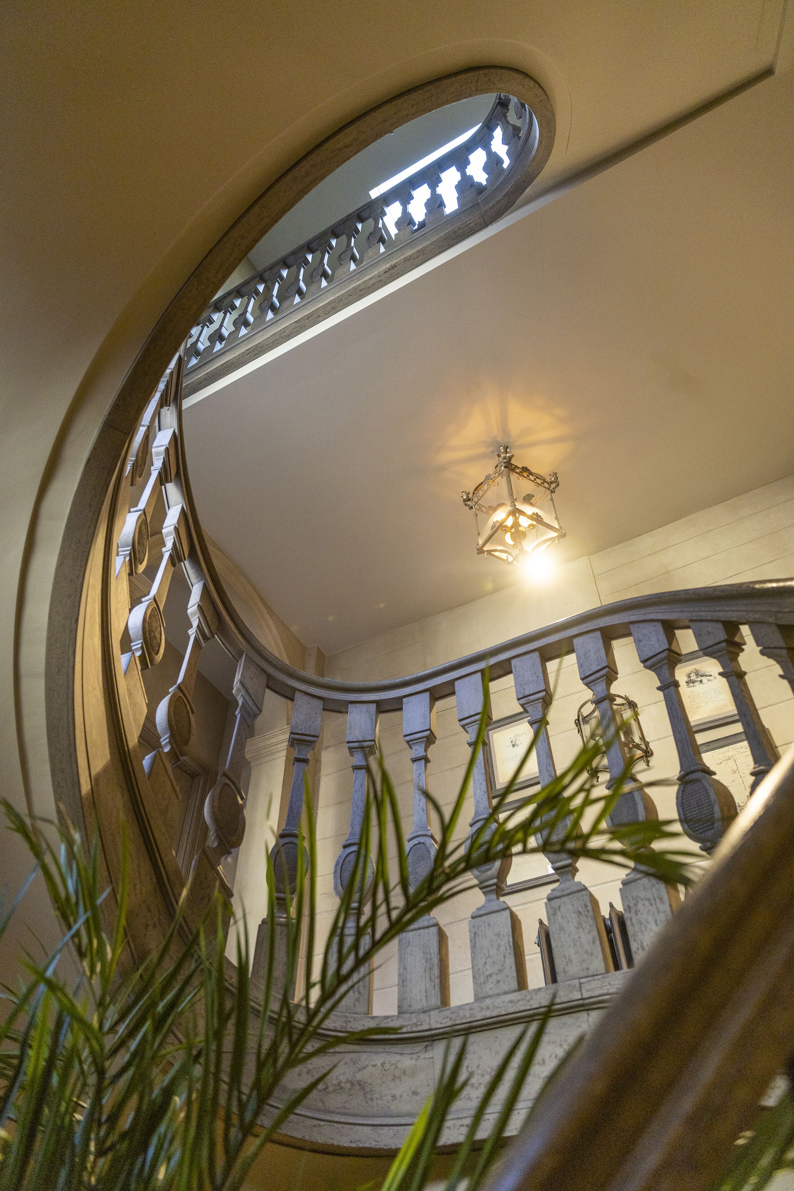 Una escalera curva con barandilla, un accesorio de iluminación y vistas al piso superior.