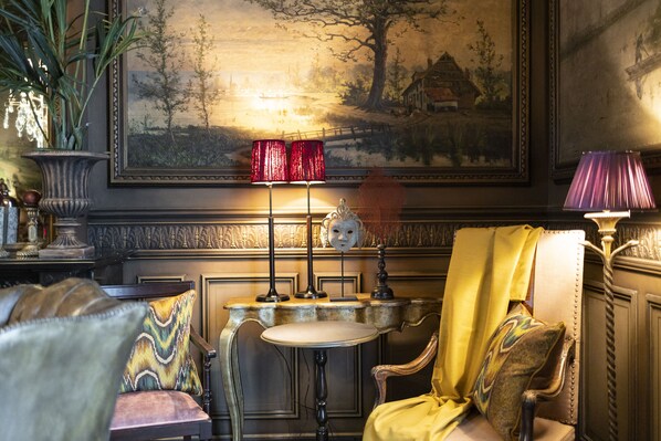 A room with a round table, two chairs, a lamp, and a painting on the wall. - Cobergher Hotel (Kortrijk)
