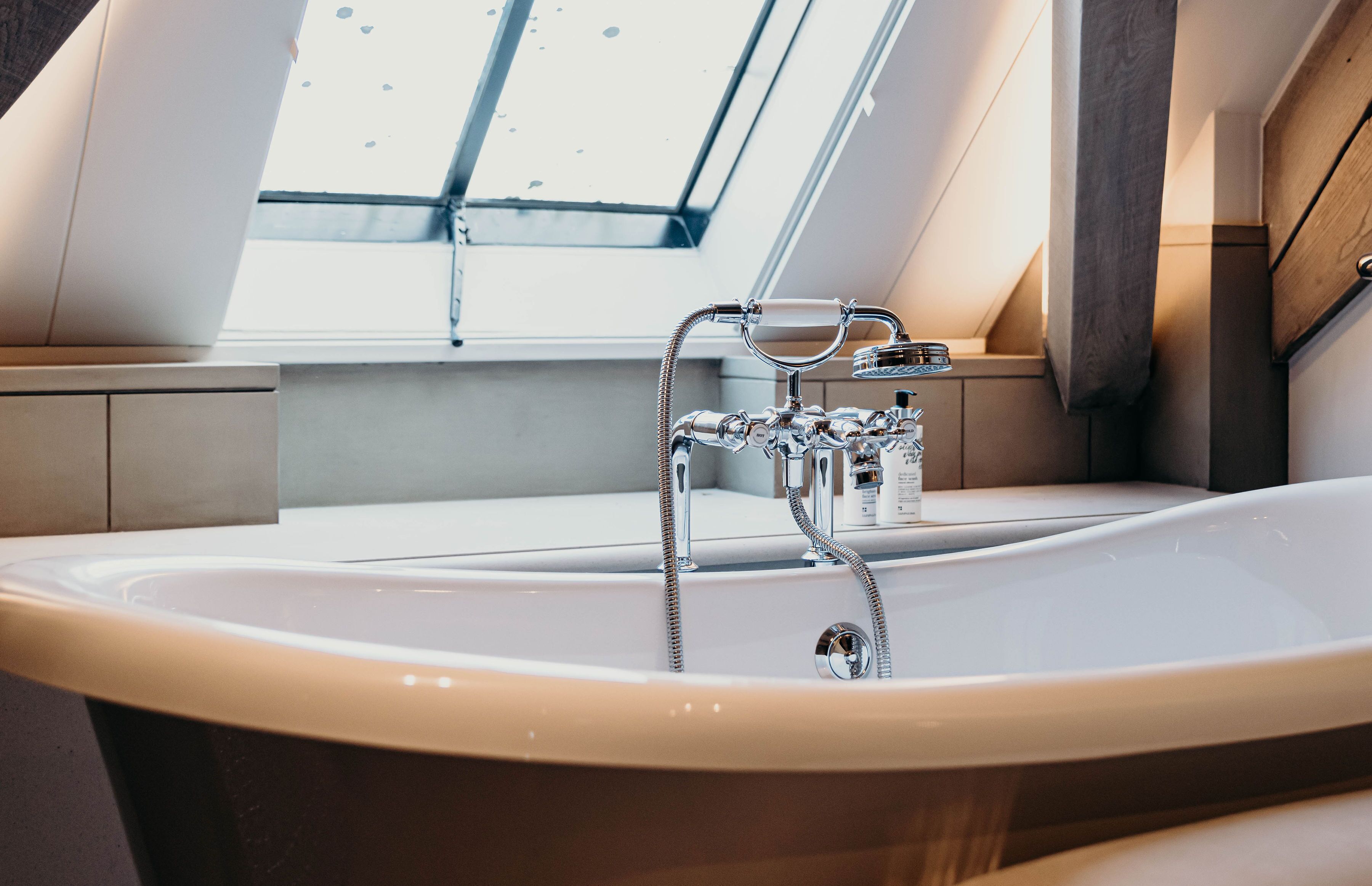 Un baño moderno con tragaluz, una bañera independiente y un mueble de tocador de madera.