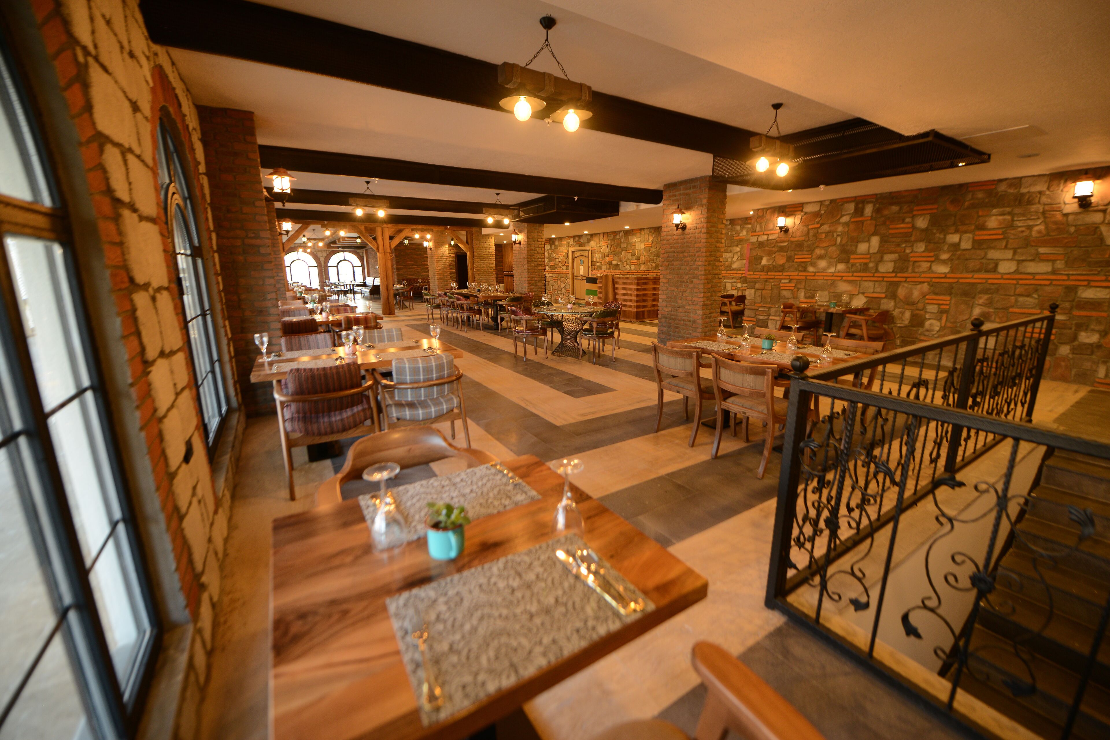 Un restaurant avec des tables et des chaises en bois, des murs en pierre et une cheminée en briques.