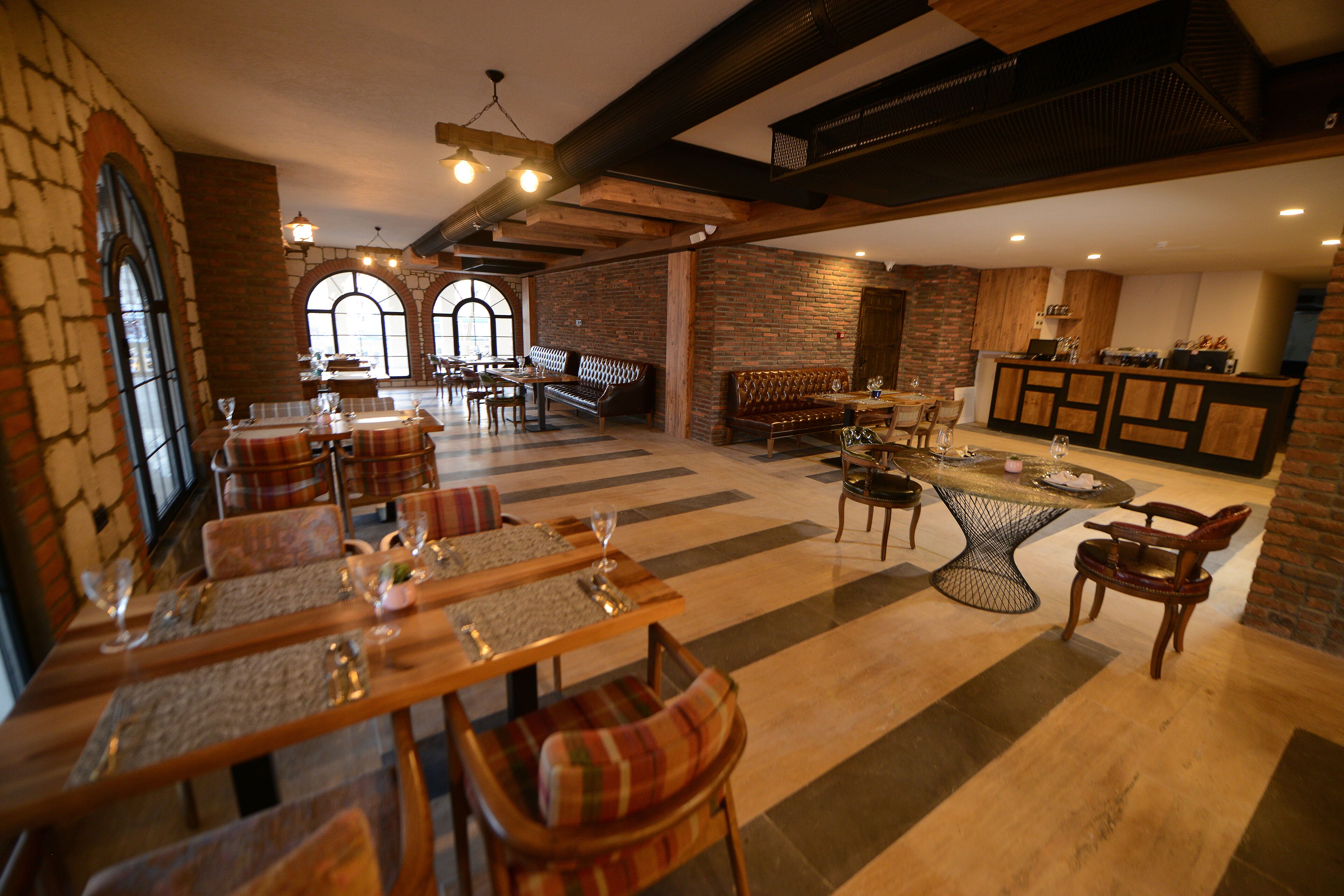 A spacious dining area with multiple seating arrangements, including tables and benches, and a bar area with stools.