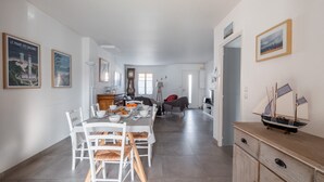 A spacious living area with a dining table set for four, a wooden cabinet, and a model ship on a dresser. - Nice family house for 6 , St Clément des Baleines (Saint-Clément-des-Baleines)