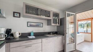 A modern kitchen with a large island, built-in cabinets, and a glass door leading to a balcony. - Nice family house for 6 , St Clément des Baleines (Saint-Clément-des-Baleines)