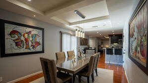 A modern dining area with a glass-top table, cushioned chairs, and abstract artwork on the walls. - LuxoStays| Sleep 14! Spacious 6BR Nr Napa(10 Bed) (Fairfield)