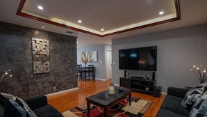 A modern living room with a flat-screen TV, dark sofas, a coffee table, and a patterned rug. - LuxoStays| Sleep 14! Spacious 6BR Nr Napa(10 Bed) (Fairfield)