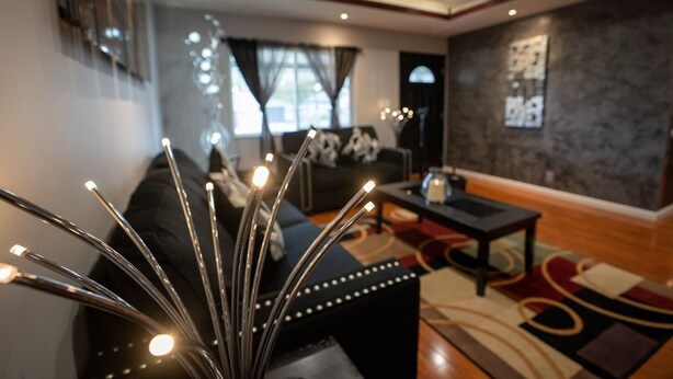 A modern living room with a black sofa, a coffee table, and a decorative light fixture.