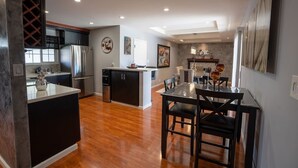 A modern kitchen with dark cabinetry, a central island, and a dining area with a table and chairs.