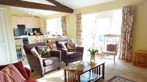 A living room with a red sofa, two armchairs, a coffee table, and a dining area with a table and chairs. - Meadow cottage- two bedrooms both ensuite and all on one level. (Rushyford)