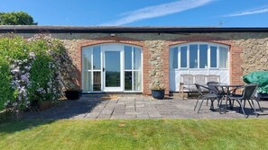 A stone building with two arched windows and a patio area with outdoor furniture. - Meadow cottage- two bedrooms both ensuite and all on one level. (Rushyford)