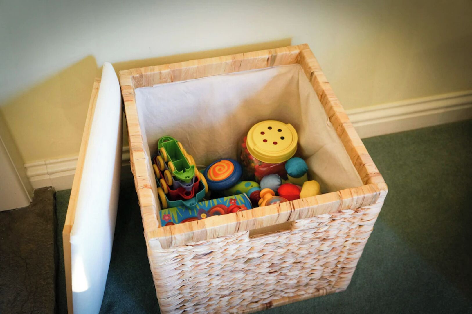 A wicker basket filled with colorful toys and a yellow container.