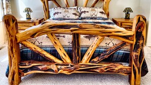 Una cama con un original cabecero de madera y ropa de cama estampada.