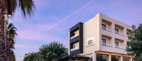 A modern hotel with a prominent 'Gallery Suites' sign, outdoor seating, and a tree-lined street.