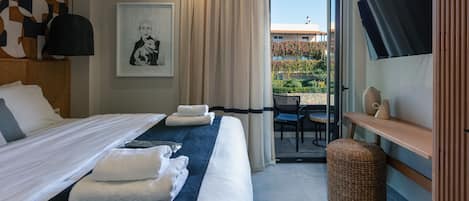 Habitación de hotel con cama, escritorio, silla, televisión y vista al exterior.