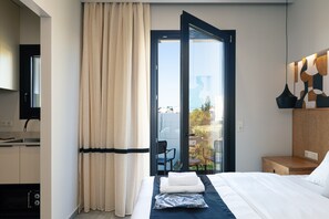 A hotel room with a bed, a bathroom with a sink, and a view of the outdoors through a glass door. - Chapter 02 Gallery Suites (Heraklion)