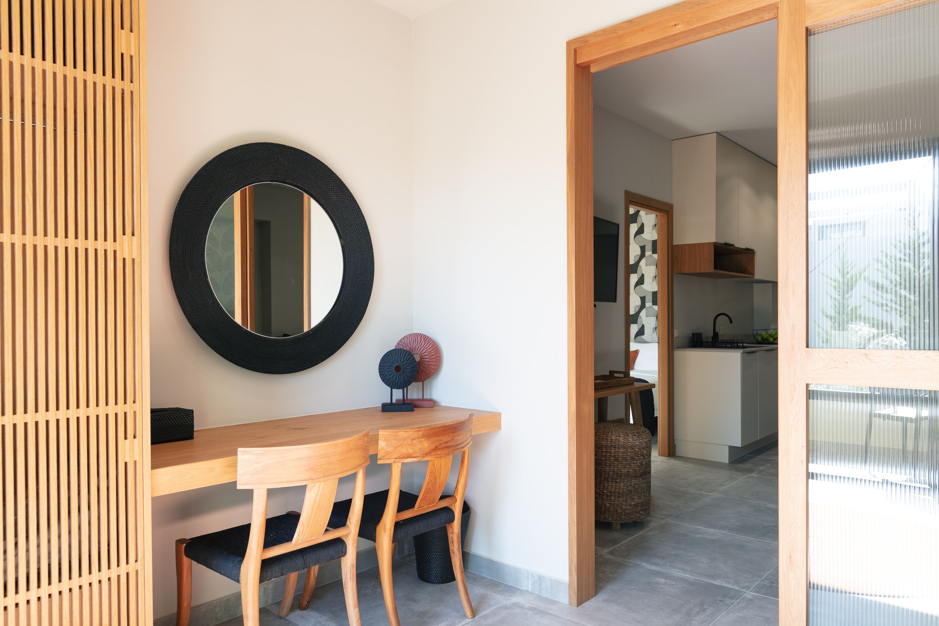 Un coin repas avec une table en bois, des chaises, un miroir rond et un objet décoratif posé sur la table.