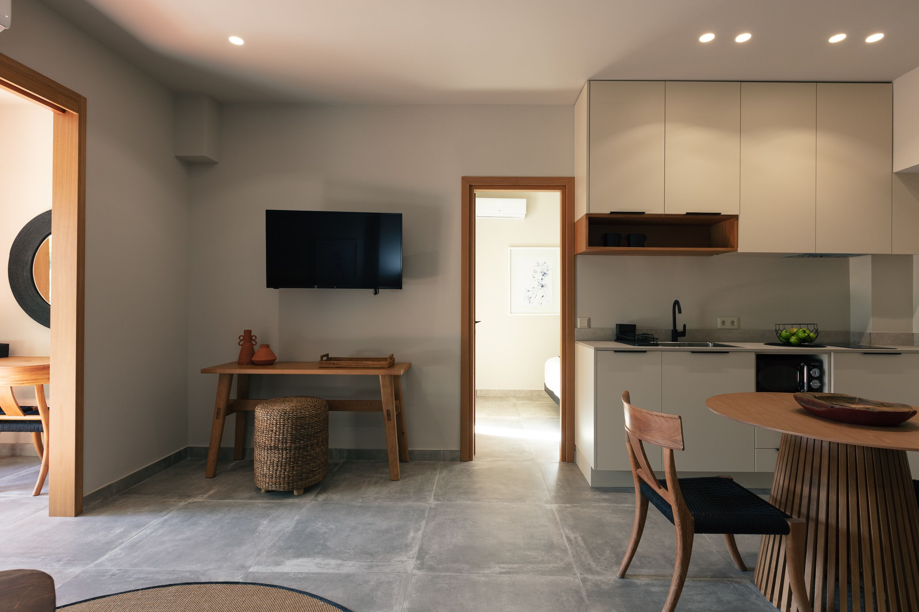 Una cocina moderna con televisión de pantalla plana, armarios de madera y un comedor con mesa y sillas.