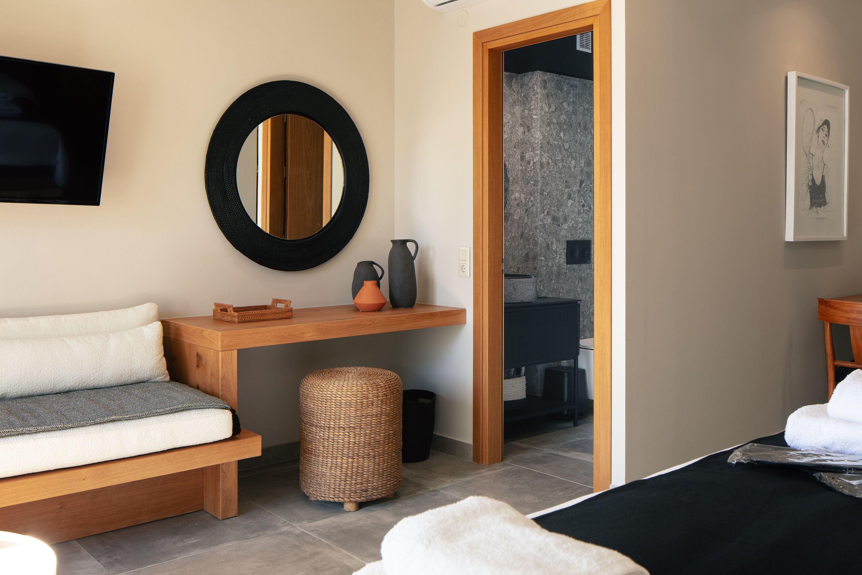 A modern bathroom with a wooden vanity, a round mirror, and a shower area.