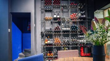 A wine cellar with shelves of bottles, a wooden table, and a blue chair.