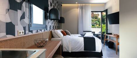 A modern hotel room with a bed, a desk, a television, and a view of the outdoors.