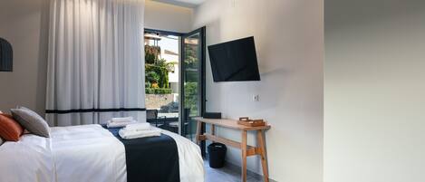 Una habitación de hotel moderna con una cama, un escritorio, un televisor y vistas al exterior.