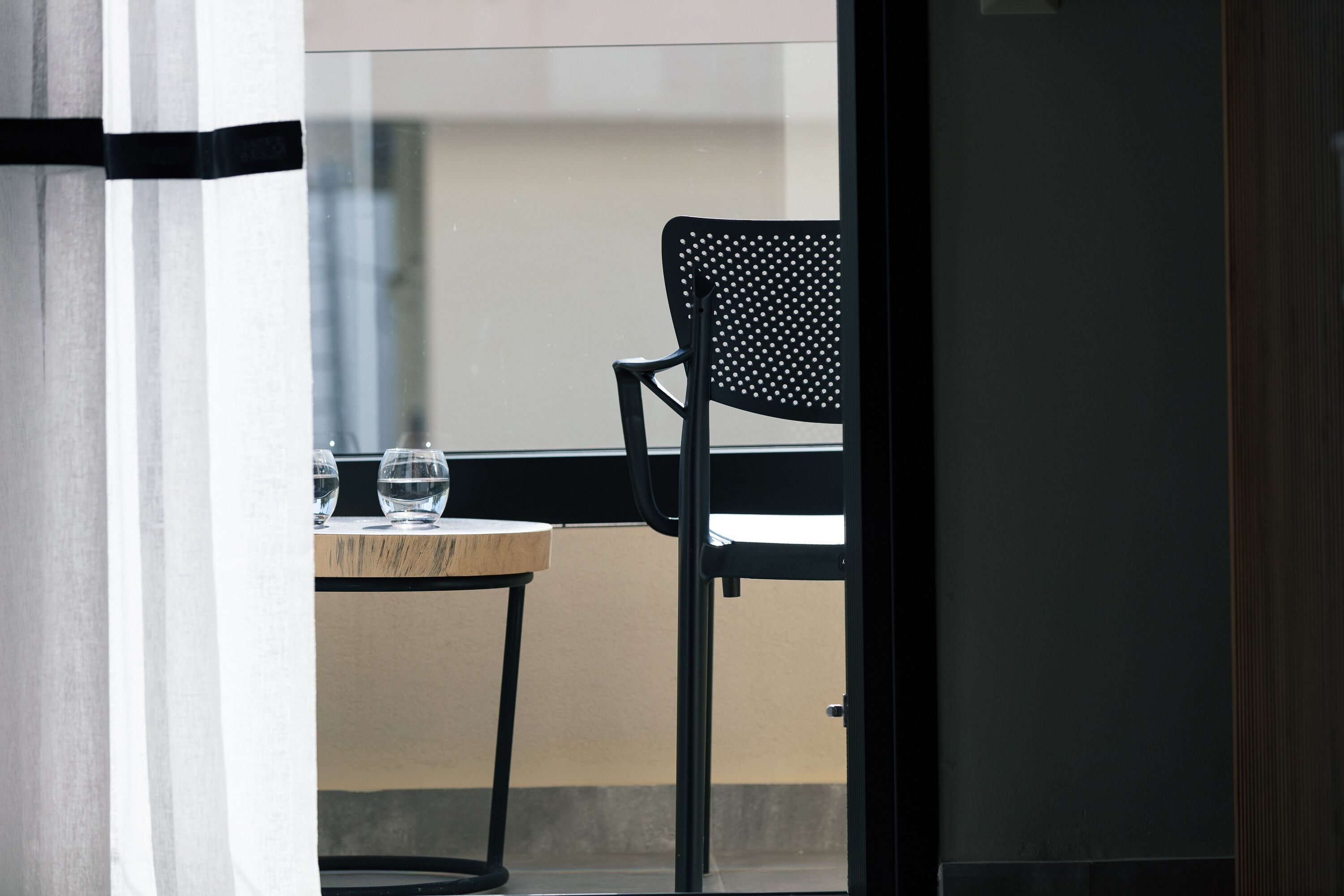 Una silla y una mesa con dos vasos en un balcón.