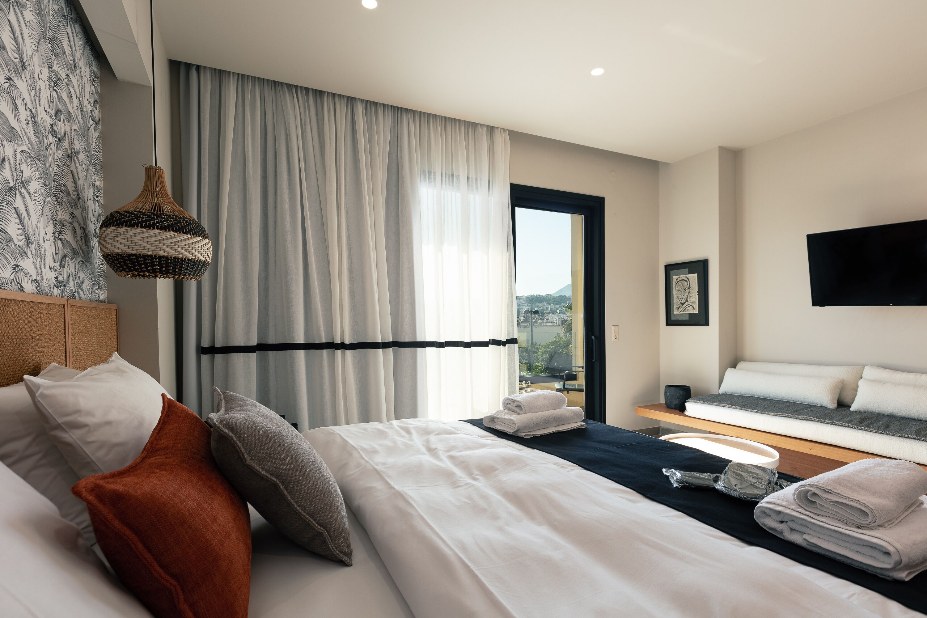 Une chambre d’hôtel moderne équipée d’un lit, d’un canapé, d’un coin repas et offrant une vue sur la ville.