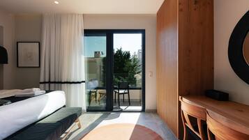 A hotel room with a bed, a desk, a chair, and a view of the outside.