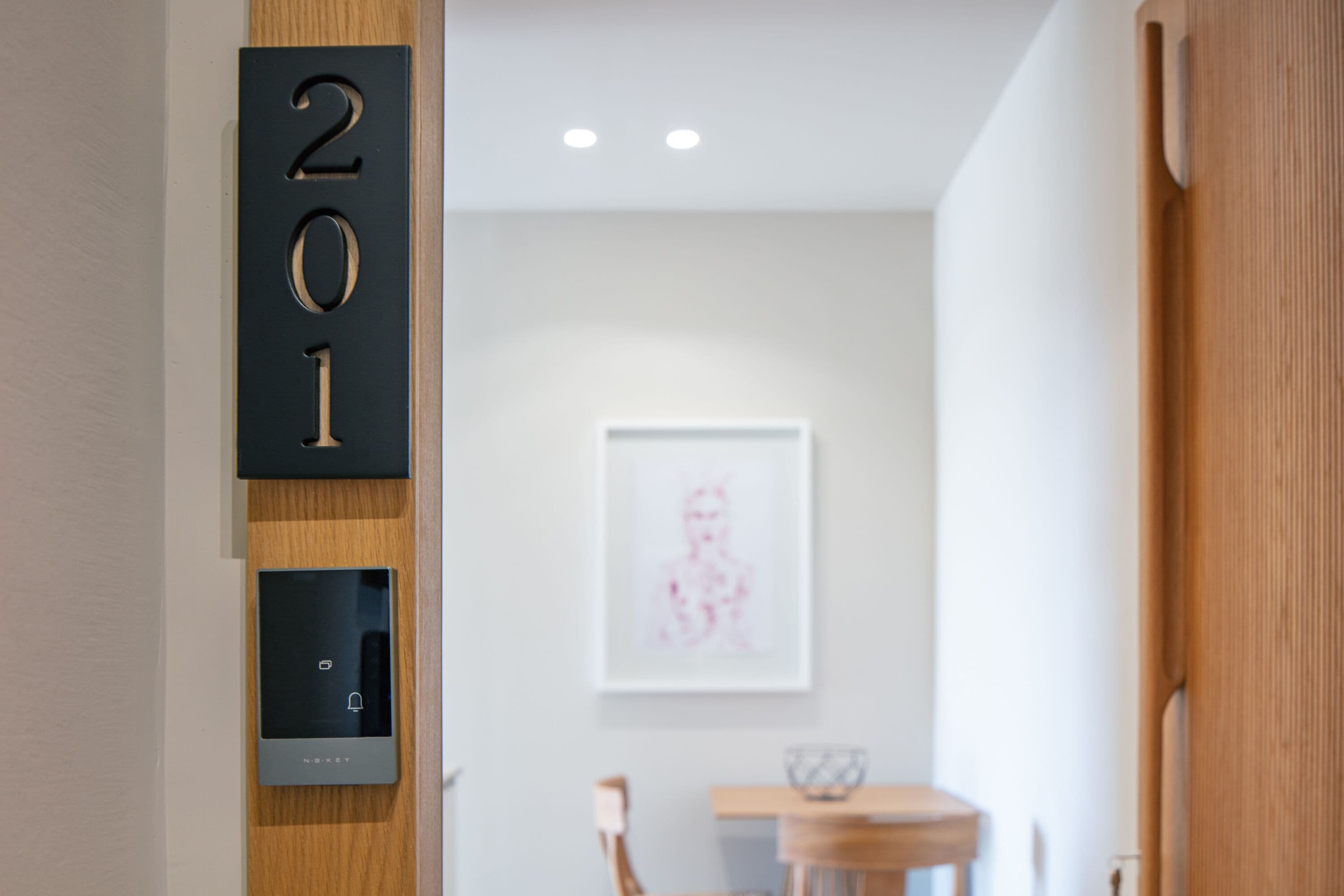 Un interior moderno con una puerta de madera, un cierre digital y una obra de arte enmarcada en la pared.