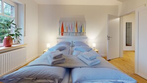Relax in a serene space with a large bed, colorful artwork, and a potted plant.