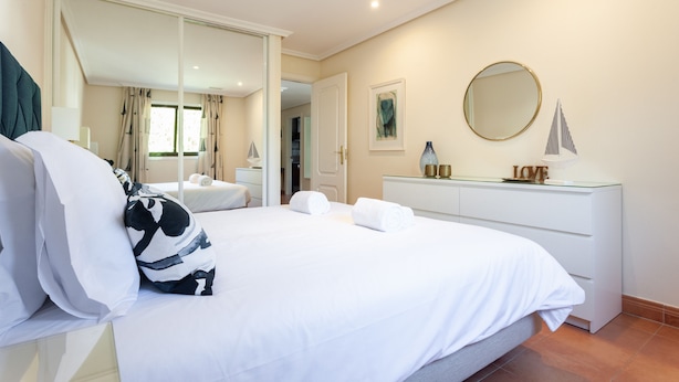 Une chambre d’hôtel avec un lit, une table de chevet, un miroir et une commode.