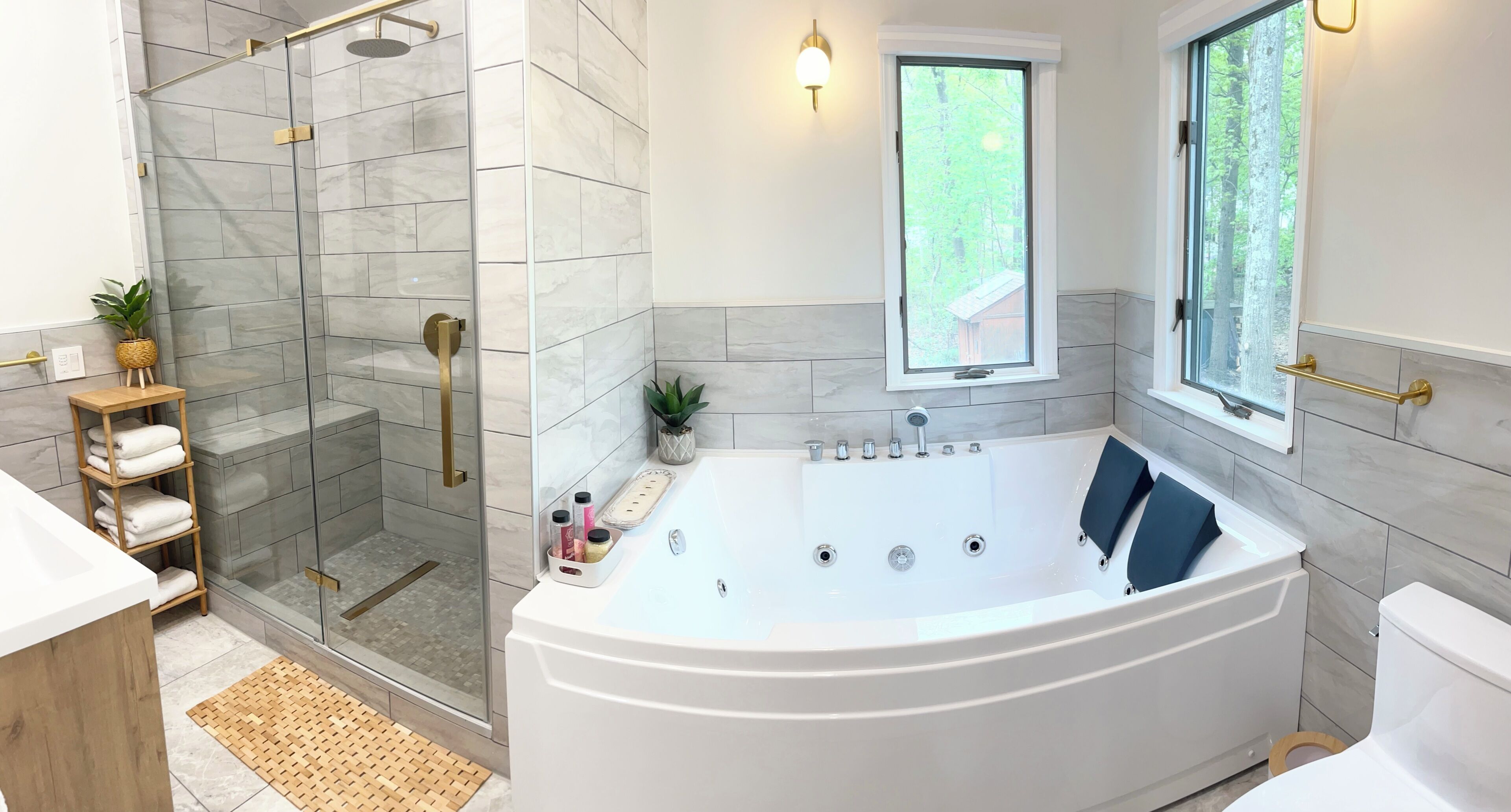 Un baño moderno con ducha a ras de suelo, bañera independiente y ventana con vistas a árboles.