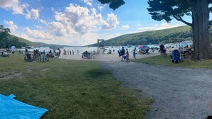 Una playa con gente, sombrillas y barcos.