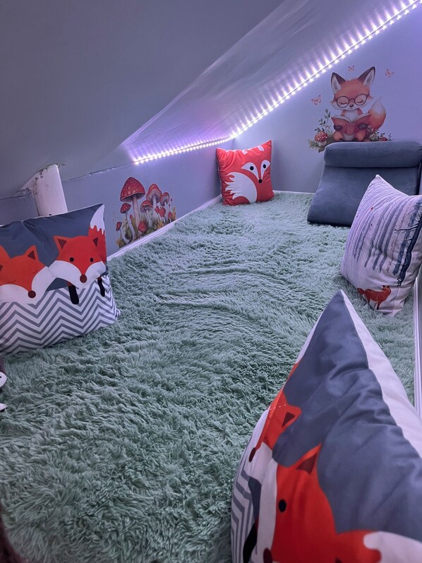 A cozy room with a fluffy green carpet, a sofa, and various pillows with animal designs.