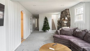Un salón amplio con una pared de piedra decorativa, un ventanal grande y un árbol de Navidad.
