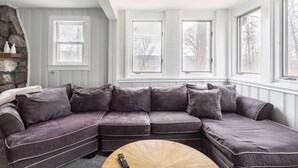 Una sala de estar moderna con un sofá modular, ventanas amplias y una chimenea de piedra.