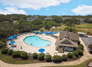 Une piscine entourée de chaises longues et de parasols, avec un bâtiment en arrière-plan.
