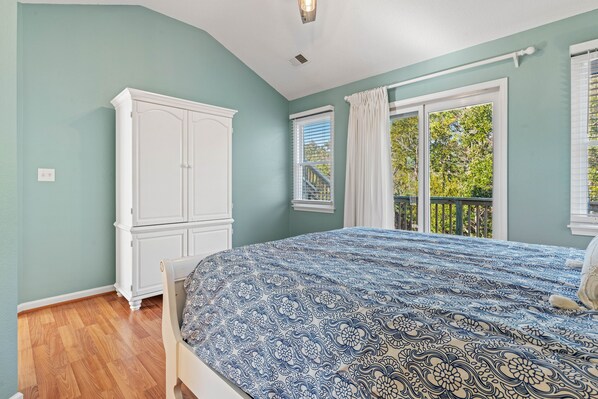 A bedroom with a bed, a wardrobe, and a window with a view of greenery.
