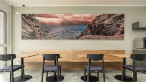 Un salón de conferencias con un cuadro de paisaje grande, una mesa de madera y cuatro sillas.
