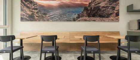 Un salón de conferencias con un cuadro de paisaje grande, una mesa de madera y cuatro sillas.