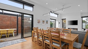 A modern dining area with a wooden table and chairs, a brick wall, and a sliding glass door leading to an outdoor space.