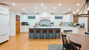 A spacious kitchen with a central island, bar stools, and a dining table.