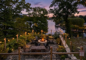 Une terrasse avec des siĂšges dâextĂ©rieur, un foyer et des guirlandes lumineuses.