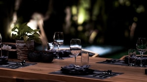 A dining table set with plates, cutlery, and glasses, with a potted plant and a candle in the background. - Villa with sunset sea view and jacuzzi - 700m from the beach! (Buleleng)