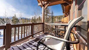 A wooden deck with a table and chairs, overlooking a snowy landscape with trees and mountains. - Ski-in/Ski-out Condo Next to Golf Course, Amazing Mountain Views from Balcony (Keystone)